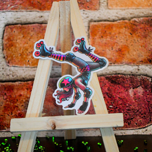 Wooden easel with colorful roller derby-themed stickers against a brick wall.
